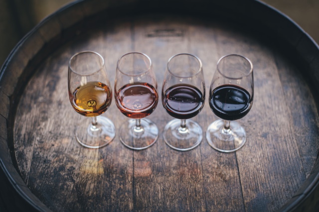 Four tasting glasses with wine on a barrel